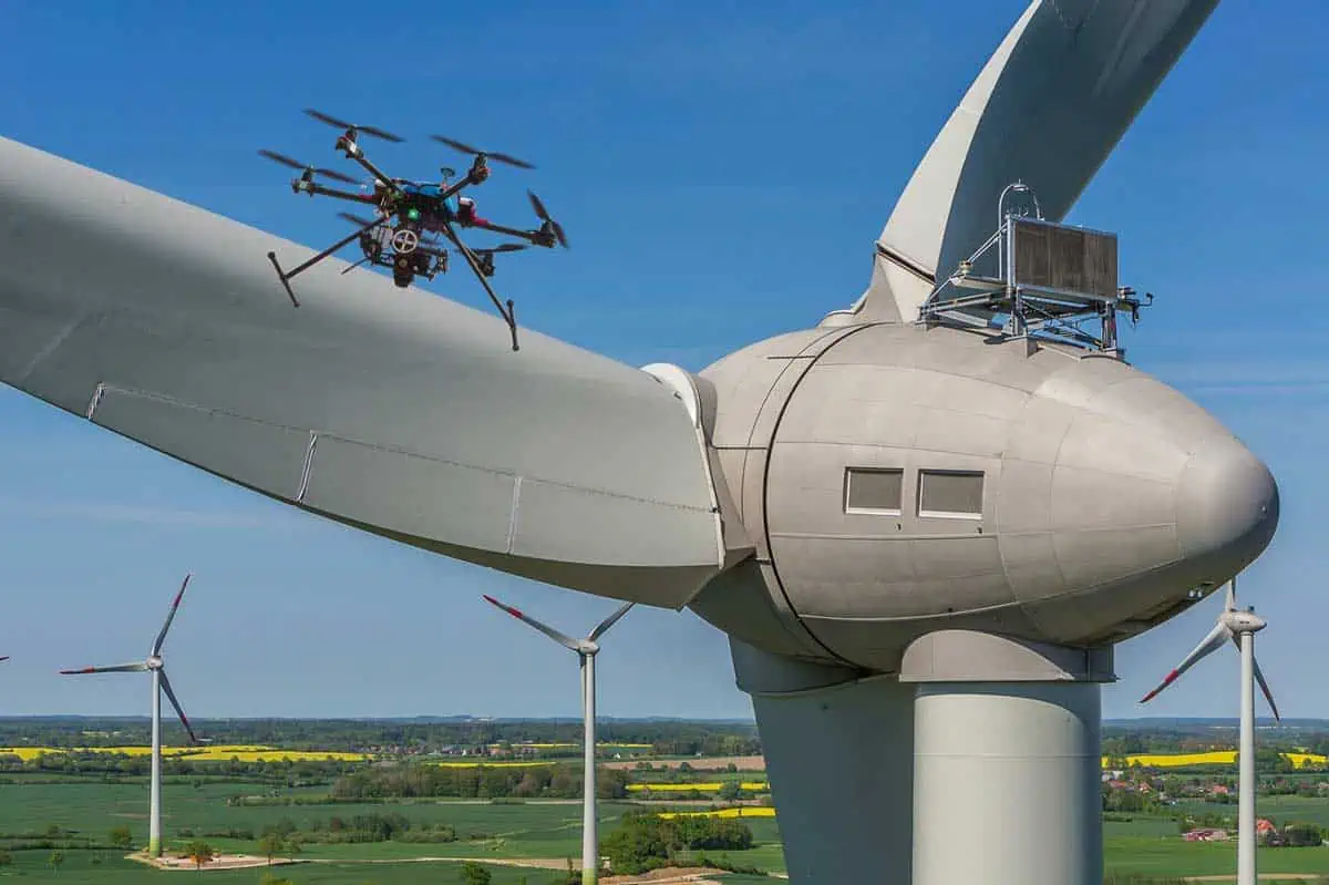 Drone flying over stationary wind turnbine.